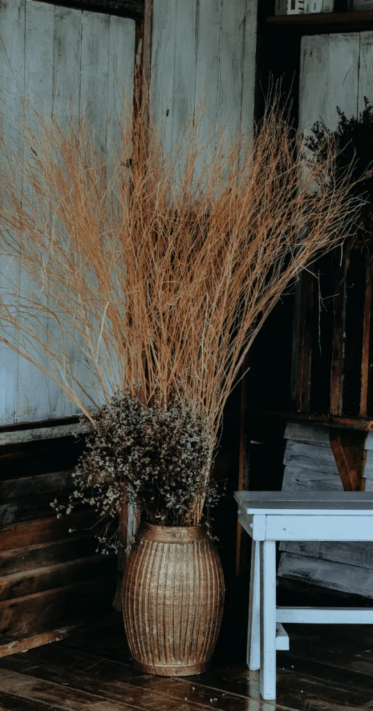 Terracotta vase filled with dried wheat stalks and pampas grass by the home entryway.