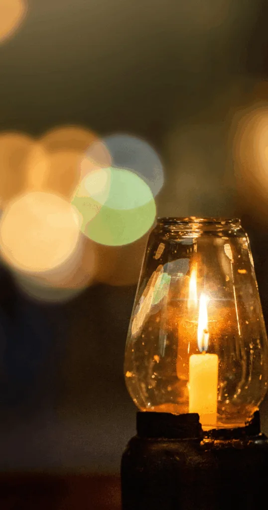 Amber string lights and rustic lanterns illuminating a cozy fall outdoor patio at dusk.