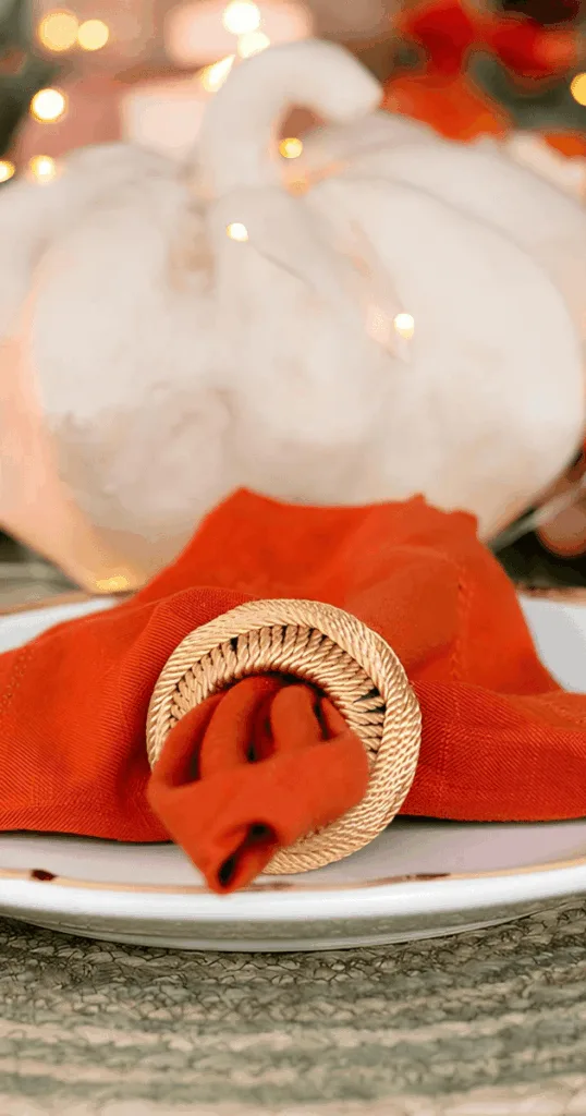 Dining table set with plaid flannel tablecloth and orange red napkins for cozy fall meals.