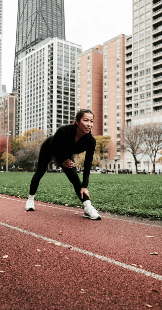 Person stretching before running  in a park covered with some fallen leaves, showing outdoor movement as part of a fall bucket list wellness routine.
